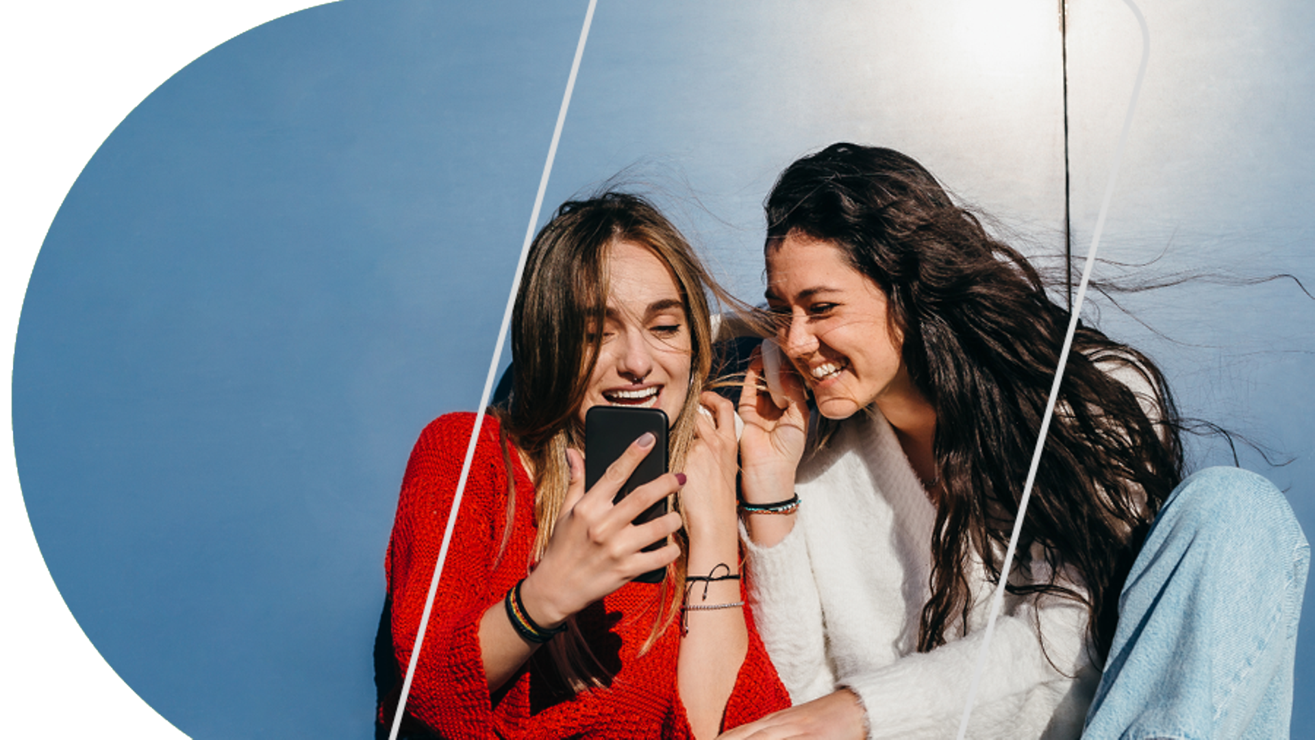 Zwei Personen mit langen Haaren schauen lachend auf ein Handy